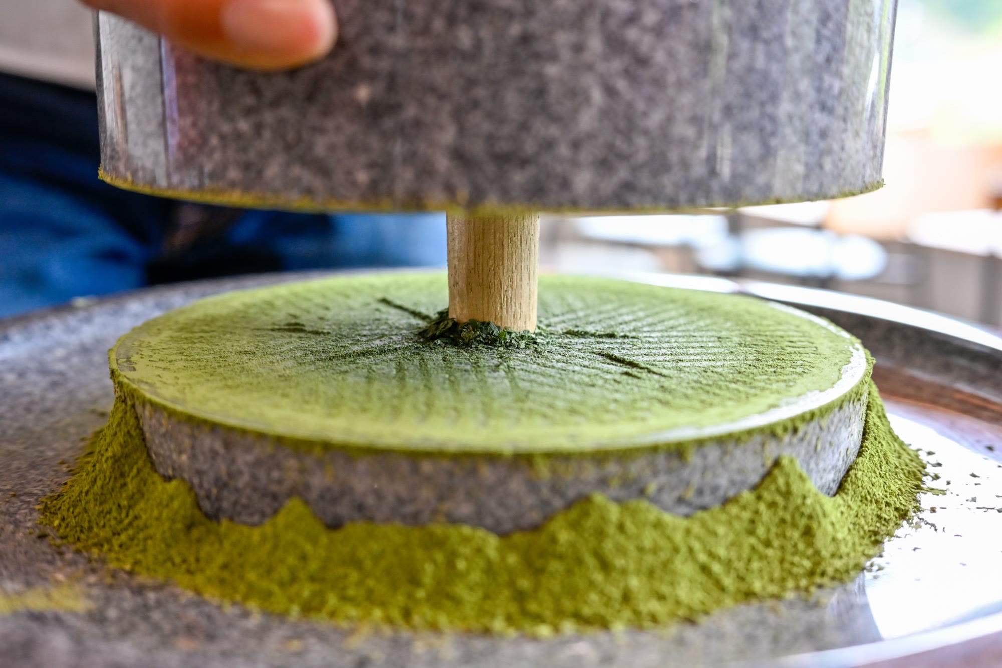 Traditional granite mill grinding tencha into fine matcha in Uji